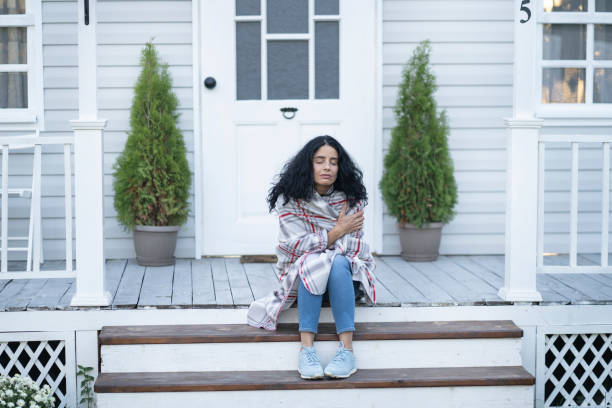 istock Woman sitting on stairs wrapped in a blanket 1180561605