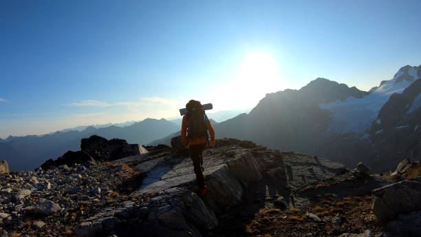istock Mountaineer hikes along rocky summit at sunrise 1180563073