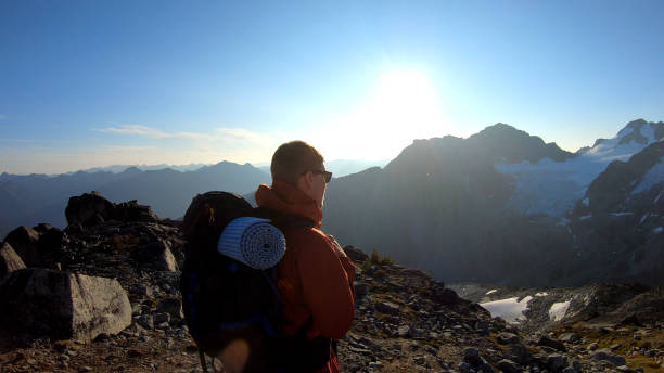 istock Mountaineer hikes along rocky summit at sunrise 1180563079