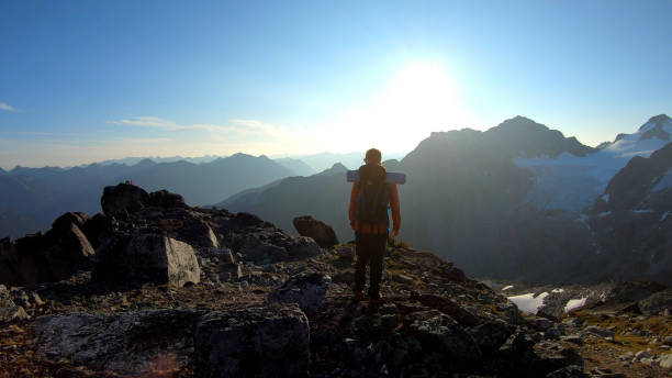 istock Mountaineer hikes along rocky summit at sunrise 1180563096