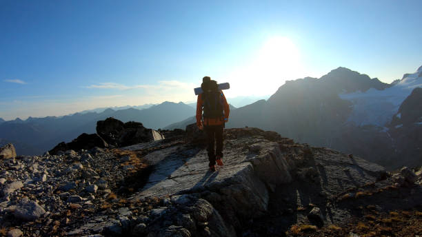 istock Mountaineer hikes along rocky summit at sunrise 1180563113