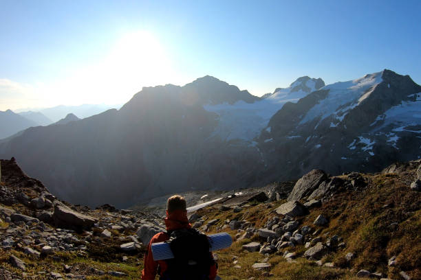 istock Mountaineer hikes along rocky summit at sunrise 1180563118