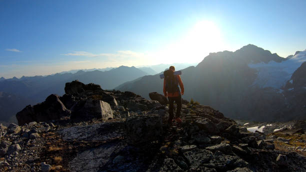 istock Mountaineer hikes along rocky summit at sunrise 1180563136