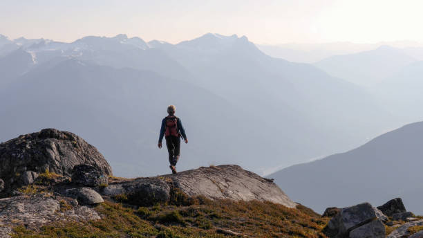 istock Mountaineer hikes along rocky summit at sunrise 1180563266
