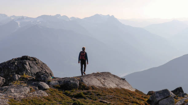 istock Mountaineer hikes along rocky summit at sunrise 1180563267