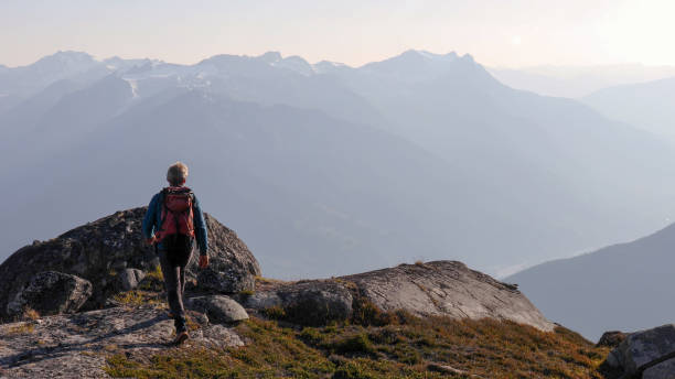 istock Mountaineer hikes along rocky summit at sunrise 1180563268