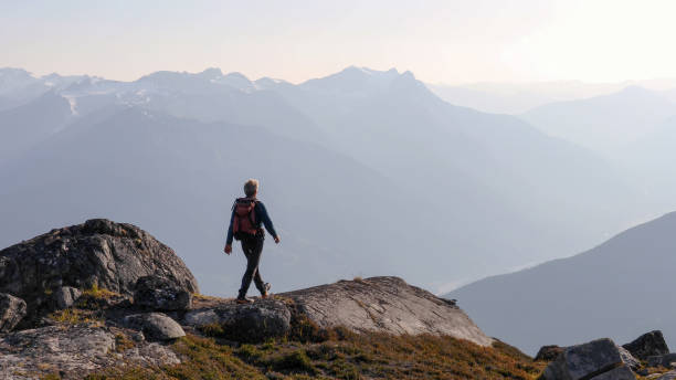 istock Mountaineer hikes along rocky summit at sunrise 1180563280