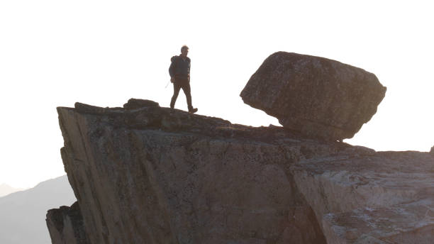 istock Mountaineer hikes along rocky summit at sunrise 1180563864