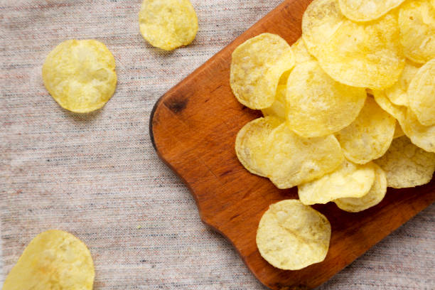 istock Yellow potato chips with salt on a rustic wooden board, top view. Flat lay, overhead, from above. Closeup. 1180566950