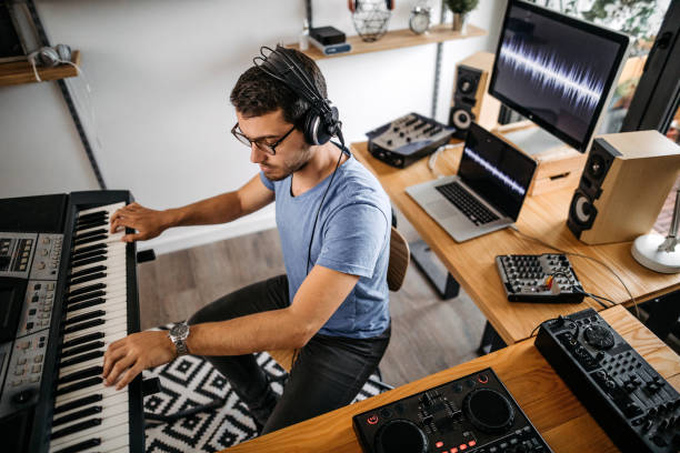 istock Man wearing headphones and playing keyboard at home recording studio 1180571983