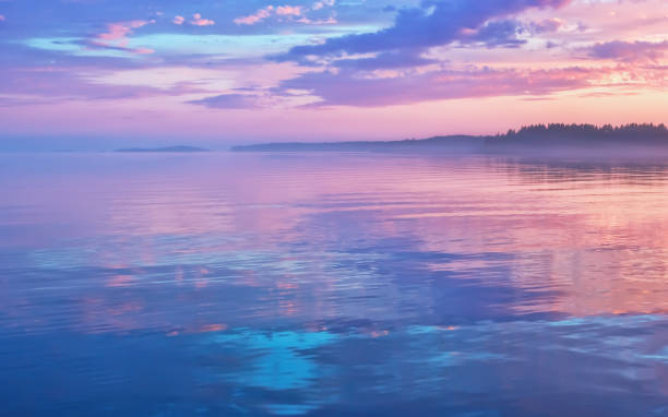 paesaggio marino nebbioso al tramonto lilla con riflesso del cielo - lake sea seascape water foto e immagini stock