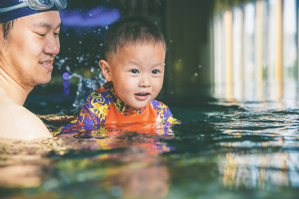 istock Asian father swimming with son. 1180581693