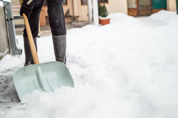 istock Man with snow shovel cleans sidewalk 1180583051