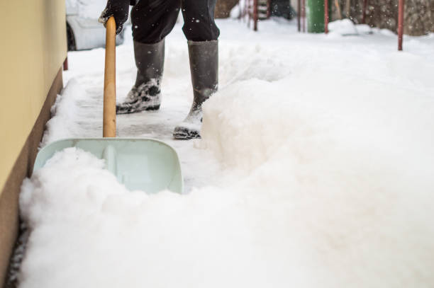 istock Man with snow shovel cleans sidewalk 1180584011