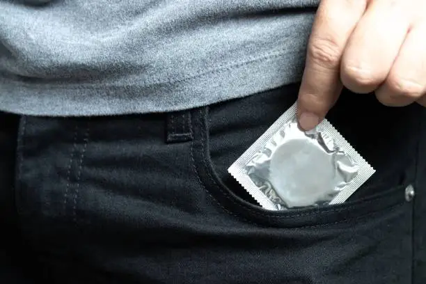 Man carry condoms taking in hand condom from jeans