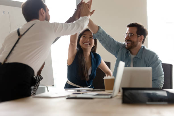 istock Overjoyed happy business team give high five at office table 1180590184