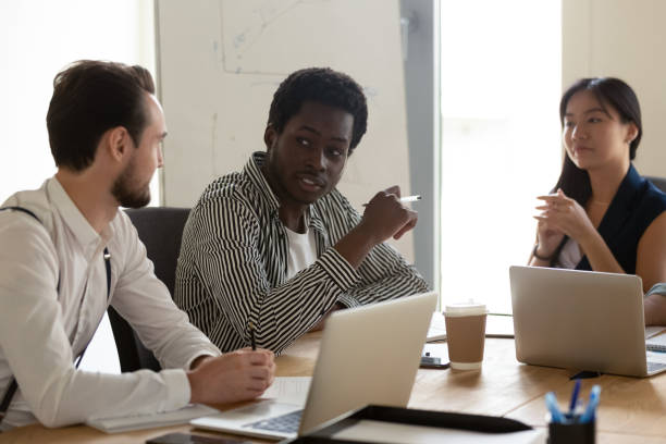istock Focused multiracial business team talking brainstorming sit at boardroom table 1180590189