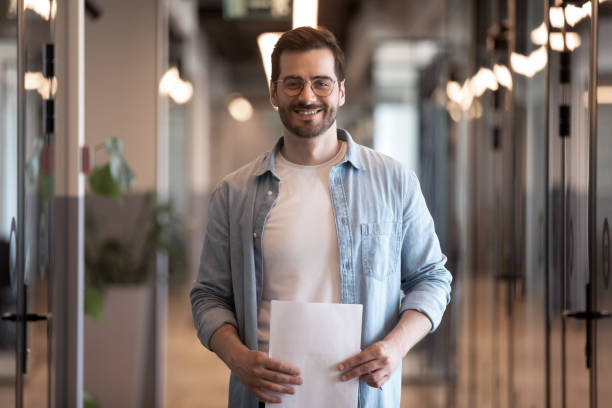 istock Confident smiling young businessman looking at camera in office hallway 1180590219