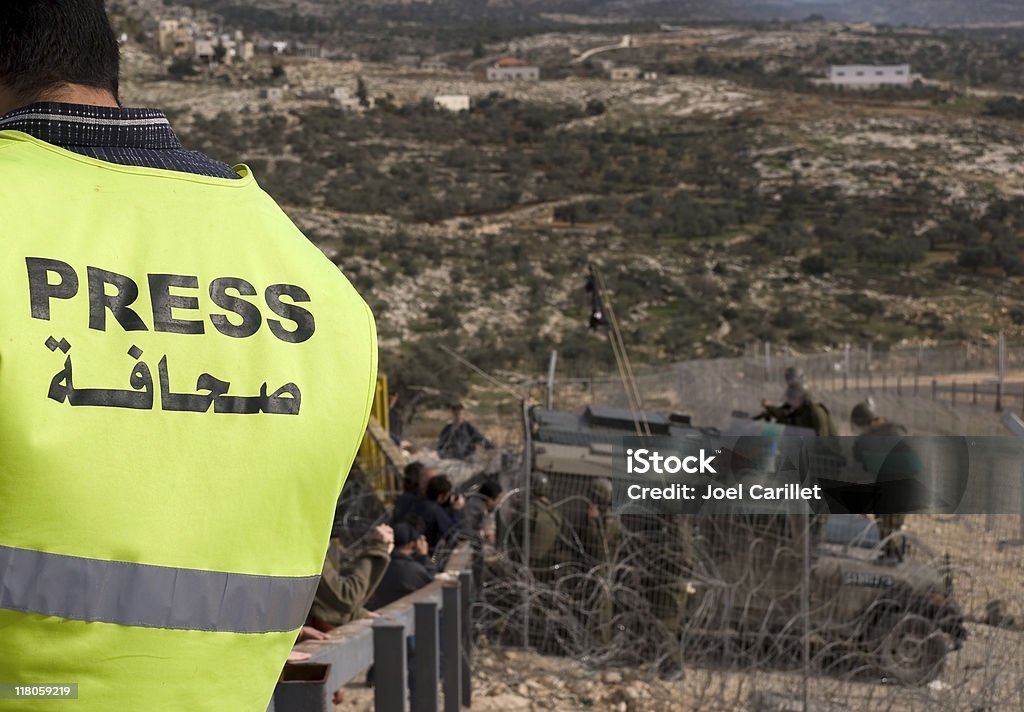 Journalist on the Field A journalist wears a clearly marked vest near military in the West Bank Journalist Stock Photo