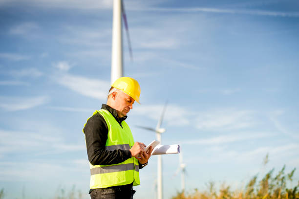 istock Electric Engineer use Digital Wireless Tablet Device with Wind turbine power Generator 1180594853