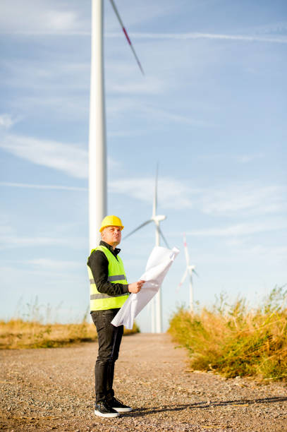 istock Electric Engineer use Digital Wireless Tablet Device with Wind turbine power Generator 1180594883