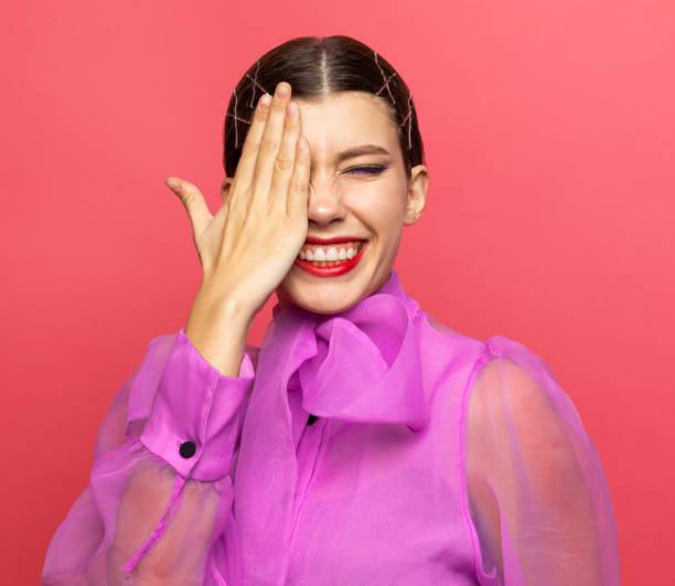 istock girl looks with one eye and laughs 1180595120