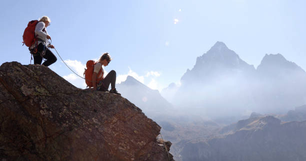 istock Mother belays daughter while climbing rock ridge, using rope 1180596518
