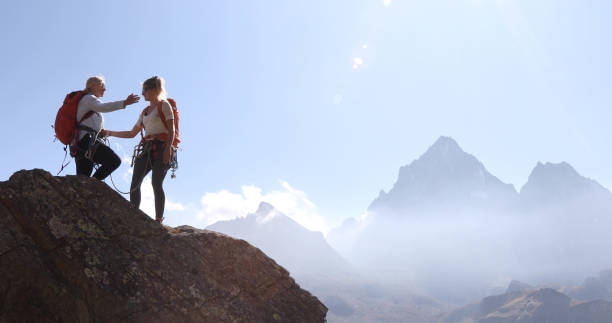 istock Mother belays daughter while climbing rock ridge, using rope 1180596524