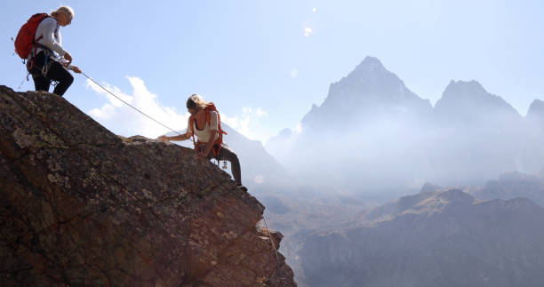 istock Mother belays daughter while climbing rock ridge, using rope 1180596545