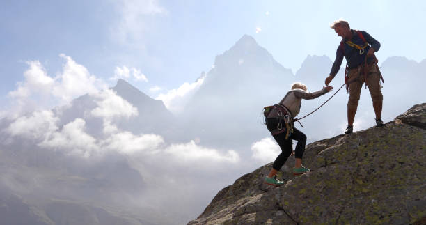 istock Mature couple climb rock ridge, using rope 1180596568