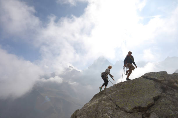 istock Mature couple climb rock ridge, using rope 1180596571