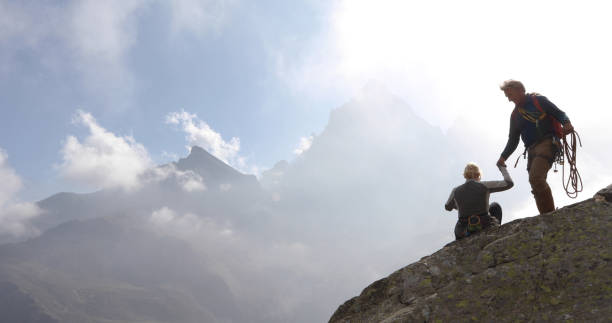 istock Mature couple climb rock ridge, arrive at summit 1180596594