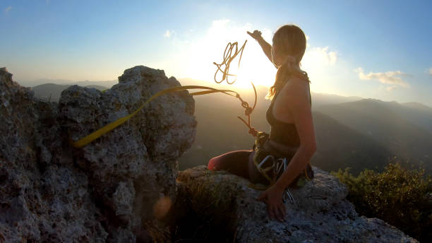 Young woman prepares to descend, throws rope from summit She looks off to distant scene; mountains and valley in distance cropped pants photos stock pictures, royalty-free photos & images