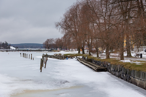 Savonlinna, Finland- 03 March 2015: View of the lake coast in winter. Piles sunk in ice. hills and forest in the background.