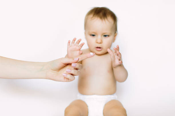 Young mother applying face kids cream on her baby girl face against light background. Hygiene, healthcare concept Young mother applying face kids cream on her baby girl face against light background. Hygiene, healthcare concept. creaming stock pictures, royalty-free photos & images