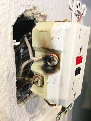 A GFCI outlet with black area from overheating. Receptacle shows the white neutral wire side. Mobilestock. Taken on mobile device.