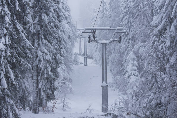 mann repariert beschädigten sessel skilift mit schnee bedeckt an nebligen schneebedeckten tag. - blizzard ice damaged snow stock-fotos und bilder