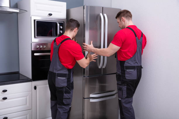 istock Two Young Male Movers Placing Steel Refrigerator In Kitchen 1180607361