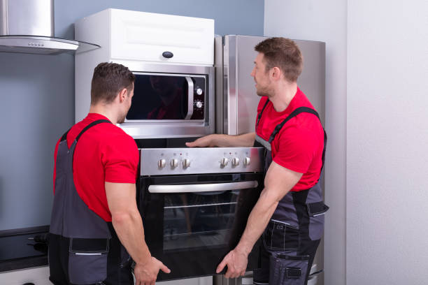 istock Young Male Worker Placing Modern Oven In Kitchen 1180607362