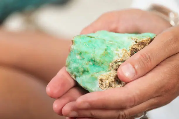 Female crystal healing therapist hand holding green Chrysoprase crystal. Chakra healing treatment with crystals.