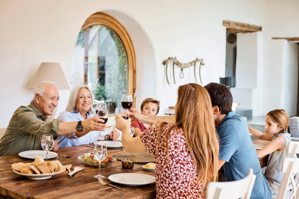 copas de vino tostadas familiares durante el almuerzo en casa - los niños y los padres brindis bebidas mientras almuerza fotografías e imágenes de stock