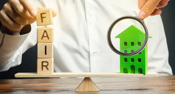 Wooden blocks with the word Fair and a wooden house. Fair value of real estate and housing. Property valuation. Home appraisal. Housing evaluator. Legal transparent deal. Apartment purchase / sale.