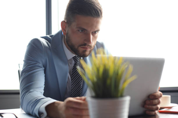 istock Good looking business man is holding laptop while sitting in the office 1180613662