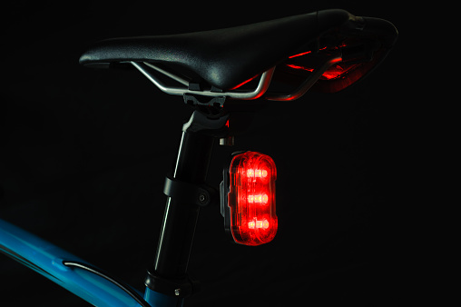 Close-up of illuminated bicycle tail light on black background