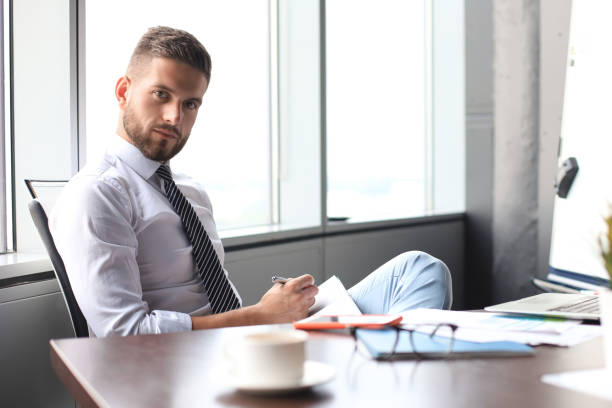 istock Focused modern businessman working and taking notes in his modern office 1180613973