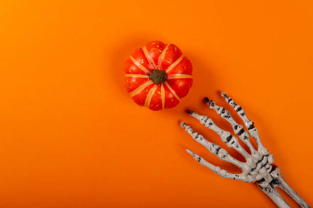 istock Halloween and decoration concept. Skeleton catching pumpkin over orange background 1180614950