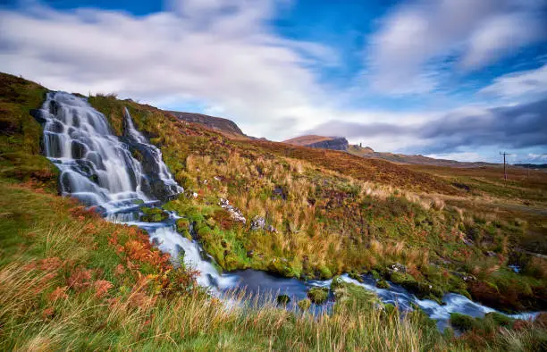 Photo of Flowing Bride's Veil Waterfall to Loch Leathan at The Storr with Old Man of Storr peak in clouds.