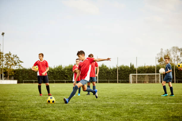 Boy kicking soccer ball on ground during training stock photo
