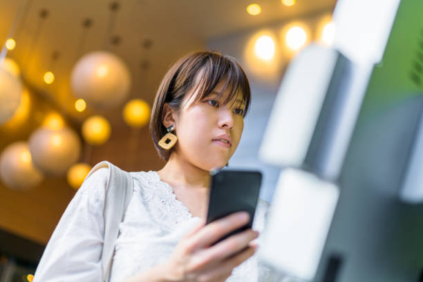 Young woman using digital device at counter A young woman is using a digital electronic check in device at a counter. hotel reception hotel service technology stock pictures, royalty-free photos & images