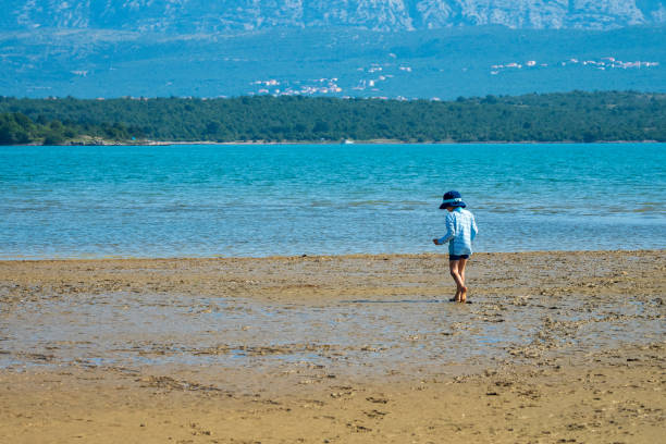 istock Little boy exploring the beach at low tide with a scenic landscape as background - Soline, Krk, Croatia 1180623105